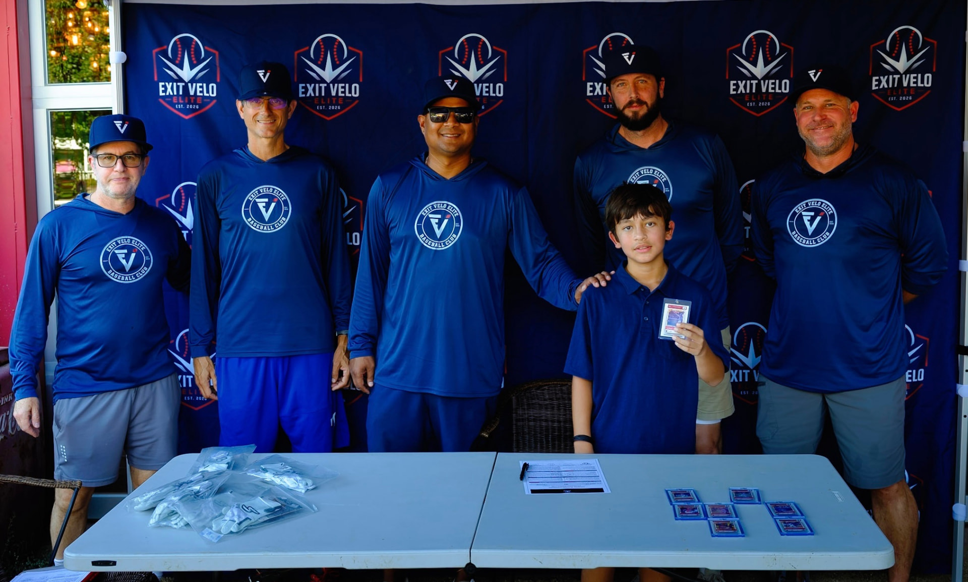 Coaches with a young signee at the club backdrop