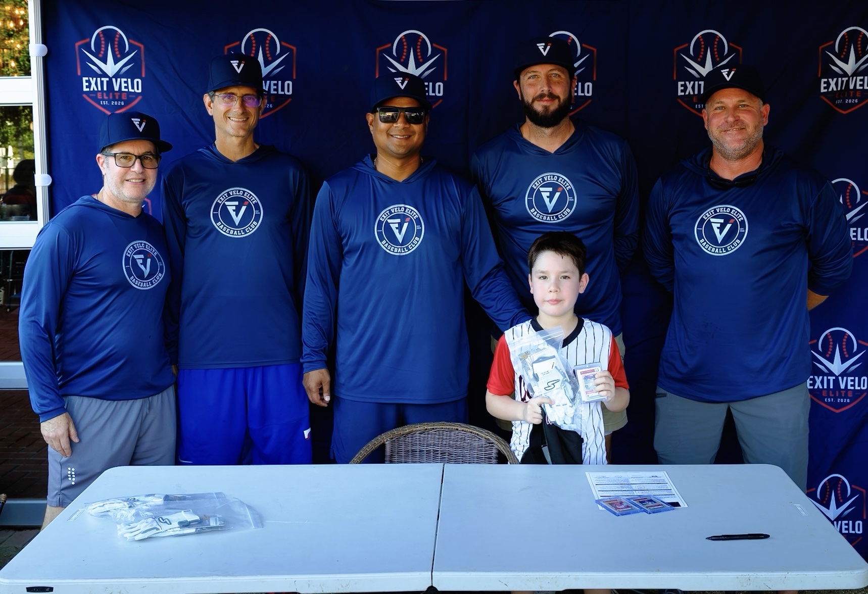 Coaches and a young player at the Exit Velo Elite signing table